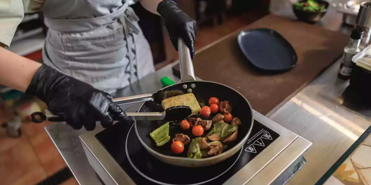 Woman cooking cheese vegetables in a frying pan on the stove with spray oil